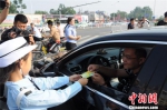 “萌娃交警”向过往车辆发放安全行车卡片。　韩波 摄 - 中国新闻社河北分社