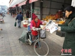 杜鸣凤在佳农市场卖报。李晓伟 摄 - 中国新闻社河北分社