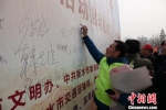 志愿者们在2019年“奉献新时代”学雷锋志愿服务活动签名墙上签名。　王鹏 摄 - 中国新闻社河北分社