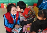 3月5日上午，文安县特教学校的孩子亲吻正给她讲故事的志愿者赵洋。 - 中国新闻社河北分社