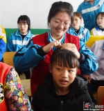 3月5日上午，文安县青年志愿者赵洋在给特教学校的孩子梳辫子。 - 中国新闻社河北分社