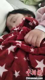 图为闫玥两岁的孩子抱着她的睡衣入睡。　李学晗 摄 - 中国新闻社河北分社