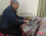 康丰民在照顾瘫痪在床的妻子。姚友谅 摄 - 中国新闻社河北分社