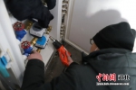 维修人员正在用电吹风给水管解冻。 王思棋 摄 - 中国新闻社河北分社