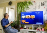 资料图：新疆乌鲁木齐市团结社区，老人通过电视订第二天的中餐。 中新社记者 刘新 摄 - 中国新闻社河北分社