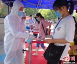 资料图：2020年7月7日，河南郑州，医务人员为进入考点的考生进行体温检查和消毒。河南省卫健委供图 - 中国新闻社河北分社