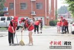 志愿者在清扫小区路面垃圾。 张明月 摄 - 中国新闻社河北分社