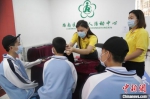 8月30日，耳聋三胞胎在工作人员的帮助下，接受新换上的人工耳蜗声音处理器调试。　施疑 摄 - 中国新闻社河北分社