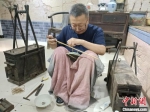 郝立新在用他爷爷留下的锔瓷工具修复一个晚清瓷盘。　王天译 摄 - 中国新闻社河北分社