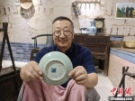 郝立新向中新网记者展示经过锔瓷修复过的晚清瓷盘。　王天译 摄 - 中国新闻社河北分社