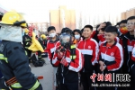 南宫市丰翼中学的学生在消防救援人员指导下体验使用正压式空气呼吸器。 - 中国新闻社河北分社