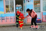 小朋友在消防队员的帮助下体验穿戴灭火防护装备。王林 摄 - 中国新闻社河北分社