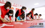 图为志愿者和小朋友在文明志愿服务条幅上签字。 刘巨雷 摄 - 中国新闻社河北分社