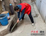 郭宏伟正在查看、清理社区井盖。 明德南社区供图 - 中国新闻社河北分社