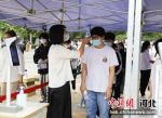图为河北省固安县第一中学考场外，考生在进入考场前进行体温检测。 吴迪 摄 - 中国新闻社河北分社
