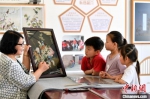 图为裴小苓正在向孩子们介绍玻璃油画历史及工艺技巧。　高丹钰 摄 - 中国新闻社河北分社