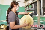 图为青县一家草编工艺品生产企业内，员工将草帽放入模具加热定型。　尹向平 摄 - 中国新闻社河北分社