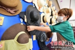 图为青县一家草编工艺品生产企业内，员工打理挂在墙上的工艺品草帽。　尹向平 摄 - 中国新闻社河北分社