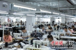 图为工人在在沧东经济开发区一家服装企业制作服装。 田博 摄 - 中国新闻社河北分社