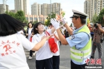 高考首日，衡水市第二中学考点，衡水交警手举向日葵，和考生互动。　黄建 摄 - 中国新闻社河北分社