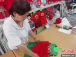 图为胜芳古镇一家儿童传统服饰店，店员正在整理刚做好的青蛙衫。　邢亚南 摄 - 中国新闻社河北分社